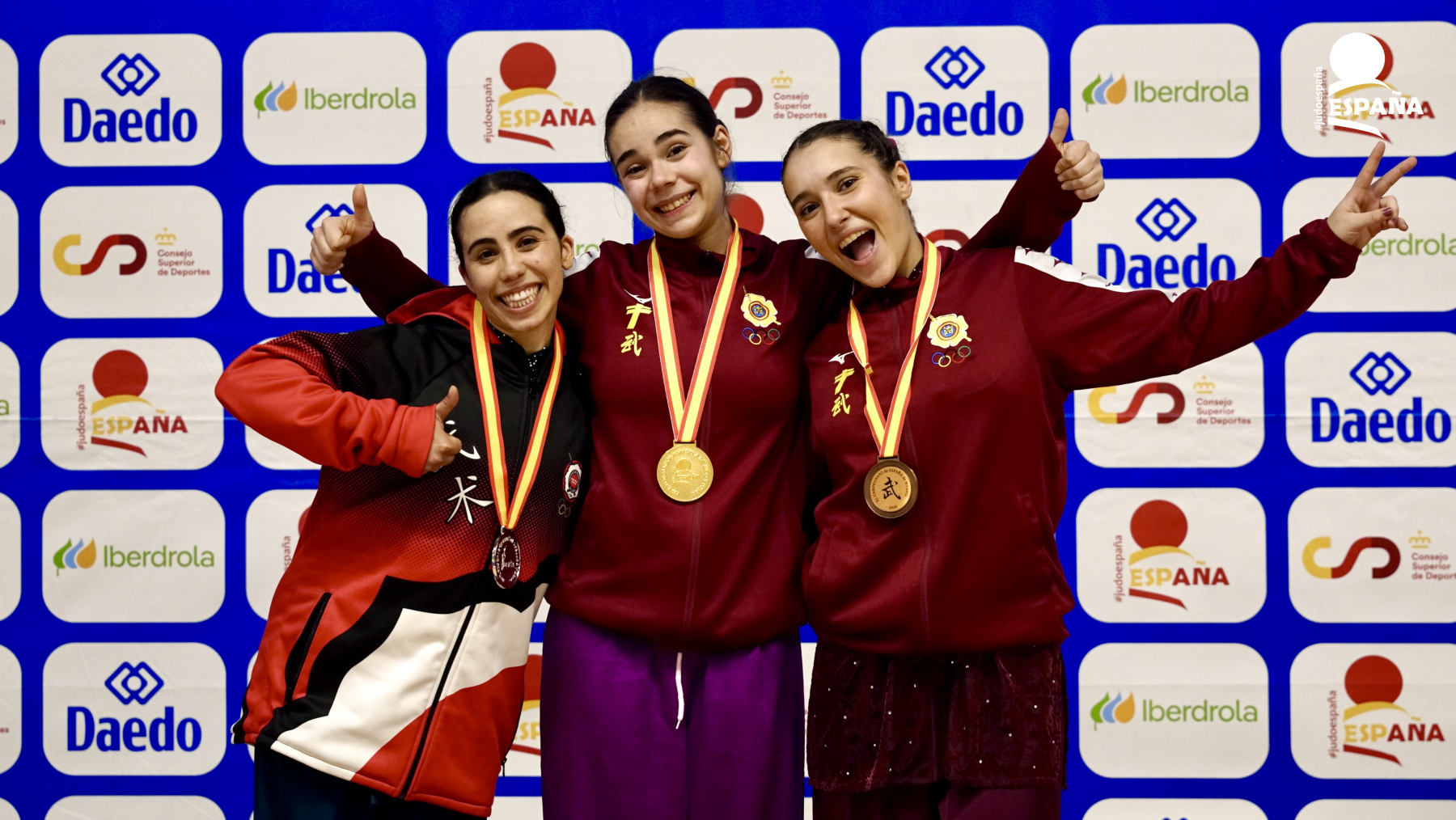 Tres atletas de wushu celebran en el podio con sus medallas en el XL Campeonato de España de Wushu 2026 en Arganda del Rey.