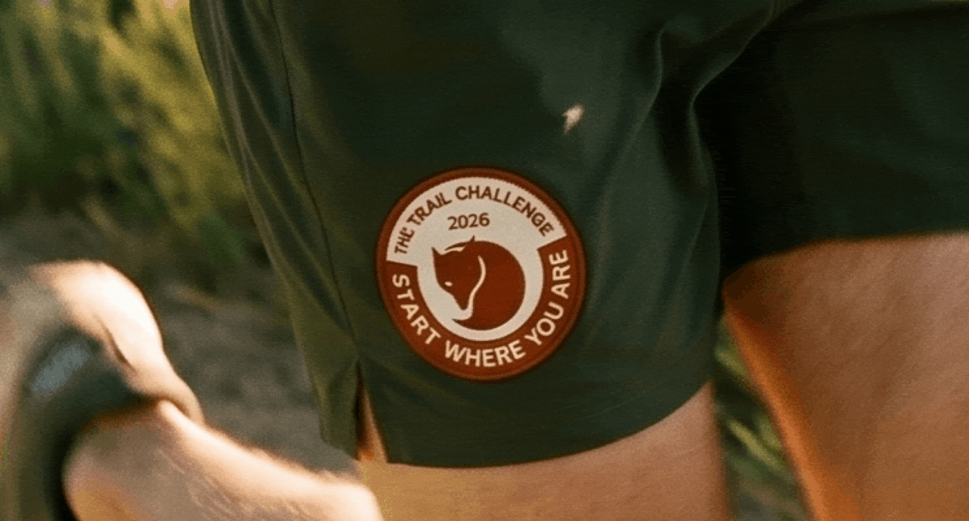 Detail shots in a gif of the Trail Challenge patch on a forest green canvas garment, lit by warm afternoon sunlight.