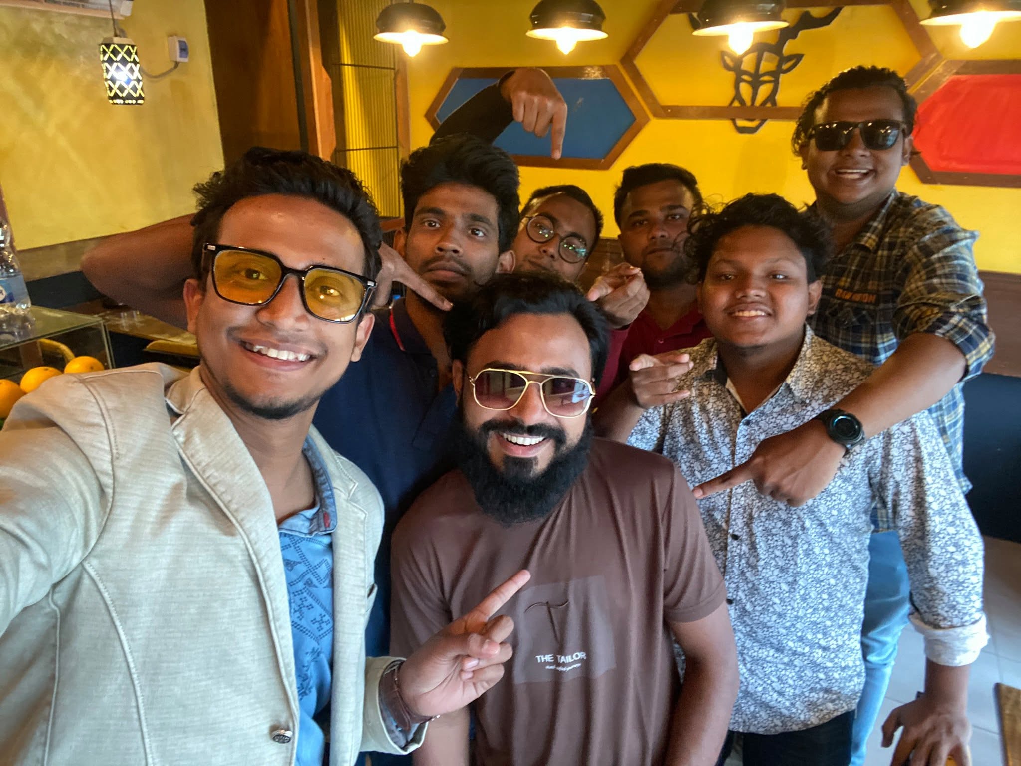 Kureghor crowding into a selfie in a café under hanging lamps.