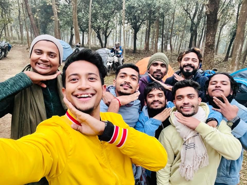 Kureghor among trees at a campsite, chins on hands for the camera.