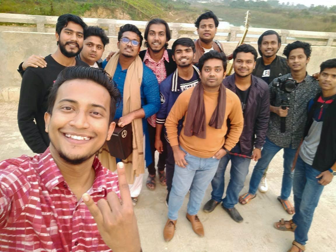A Kureghor selfie on a riverside road, a dozen of them crowding in behind the camera.
