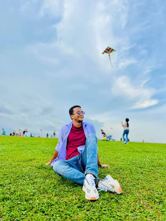 Sitting on grass with a kite in the sky, Singapore.