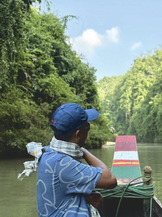 Looking out from the back of a boat on a green river, Bandarban.