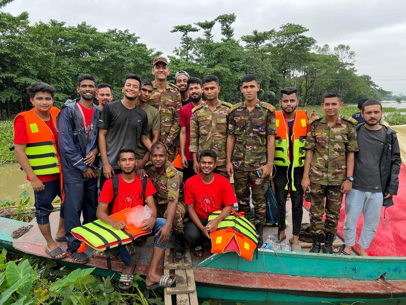 People in high-visibility vests and in camouflage uniform gathered beside the boats.