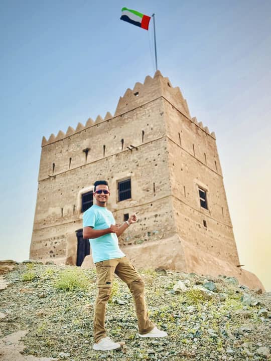 Before a stone fort under the flag, Dubai.