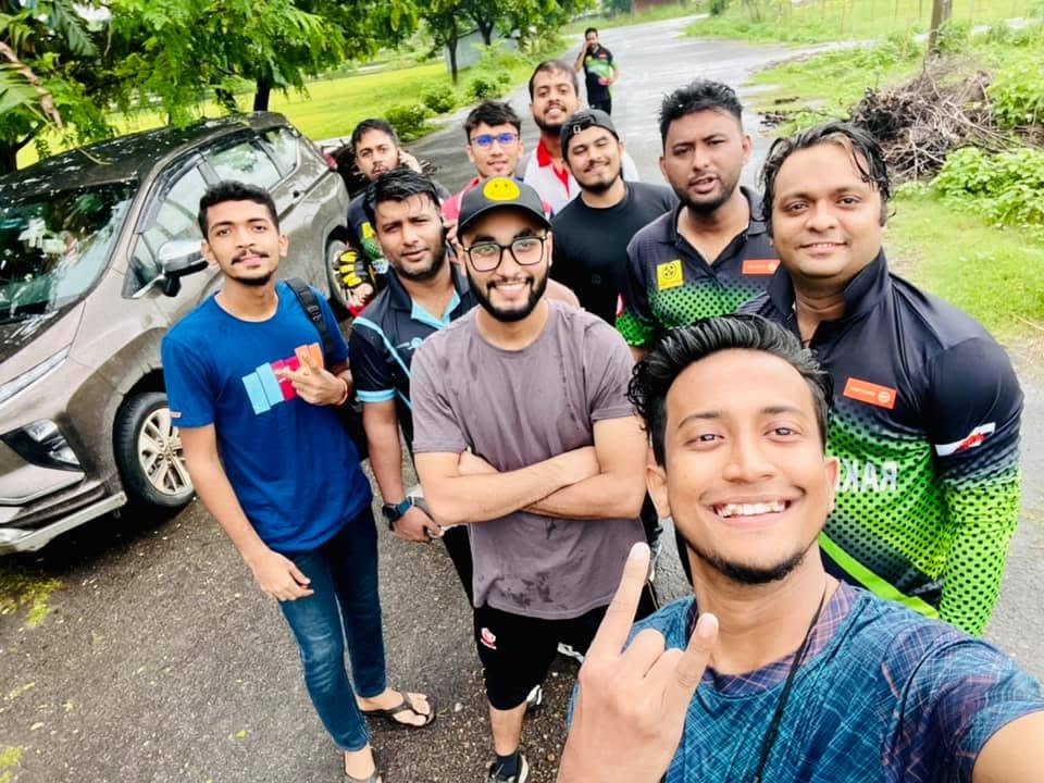 A Kureghor selfie on a wet roadside, the group spread out behind the camera.