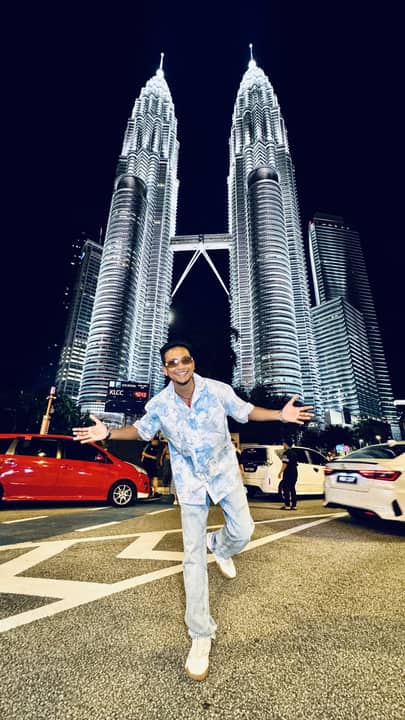 Arms wide below the Petronas Towers at night, Malaysia.