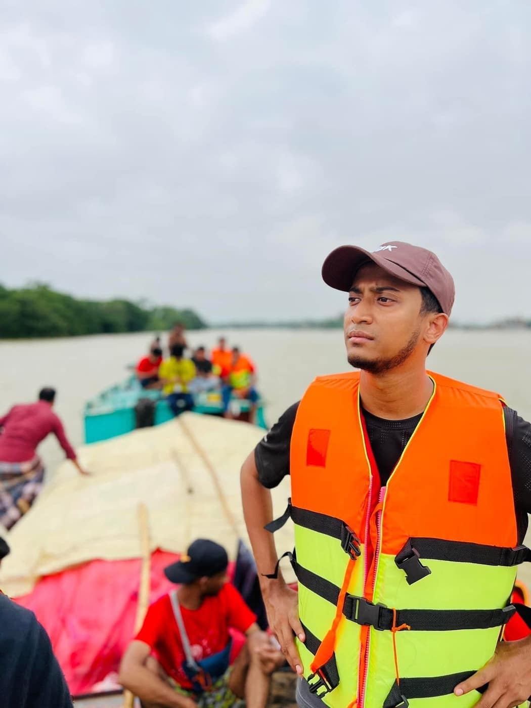Tasrif in a life jacket on a loaded boat, a second boat of people behind him.