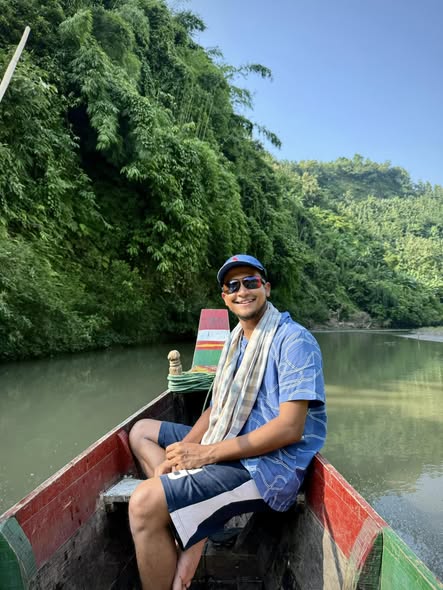 Sitting in the bow of a moored boat, forest behind, Bandarban.