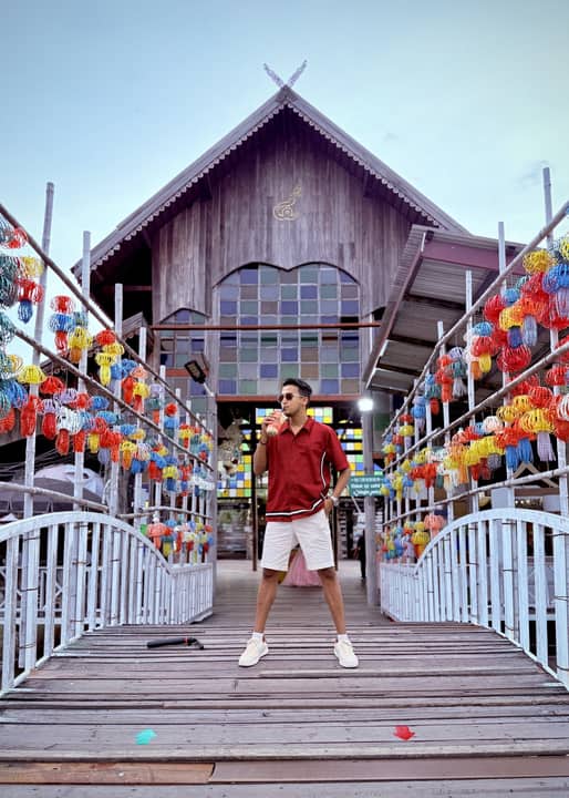On a wooden bridge hung with coloured parasols, Thailand.