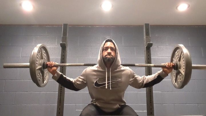 Mike, in a hoodie, engaged in a 'gut check' barbell squat during an early morning workout.