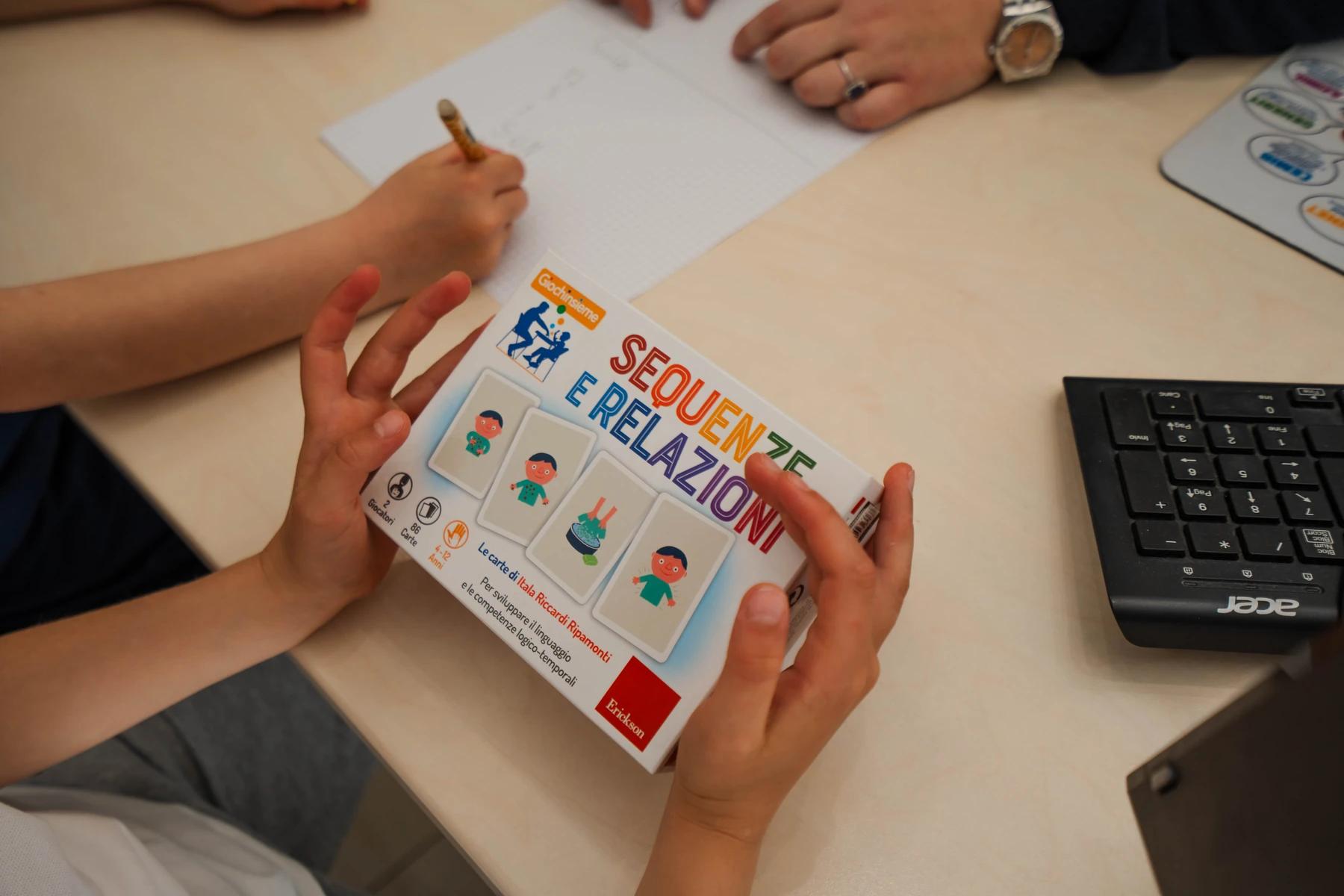 Mani di un bambino che mostra una scheda di sequenze durante la seduta di logopedia a Viterbo