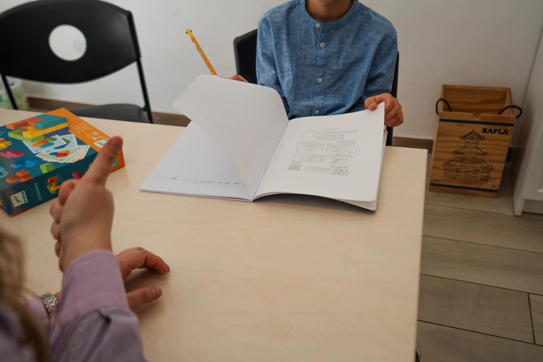 Mary segue un bambino che scrive sul quaderno nello studio di logopedia di Viterbo