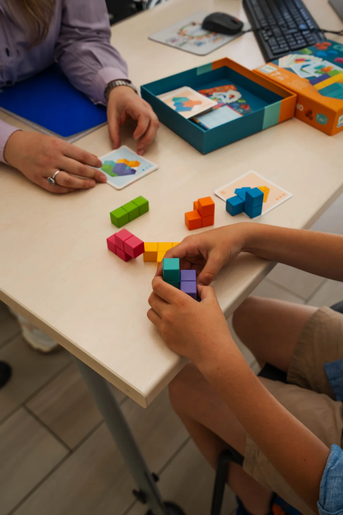 Mariangela Allegrini lavora con un bambino al tavolo durante una sessione di logopedia, materiali colorati davanti, nello studio di Viterbo