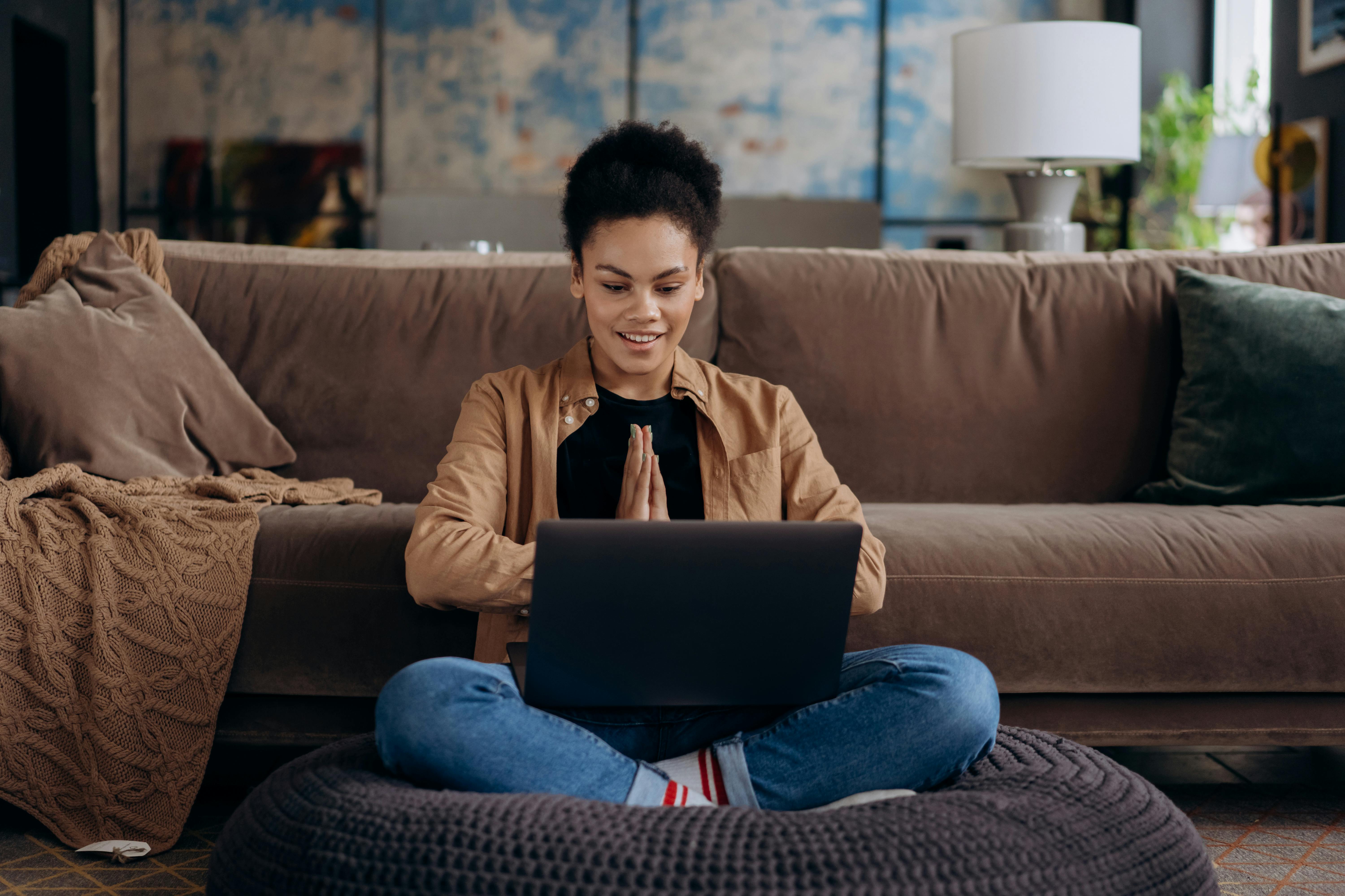 A woman sitting looking at her laptop happily.