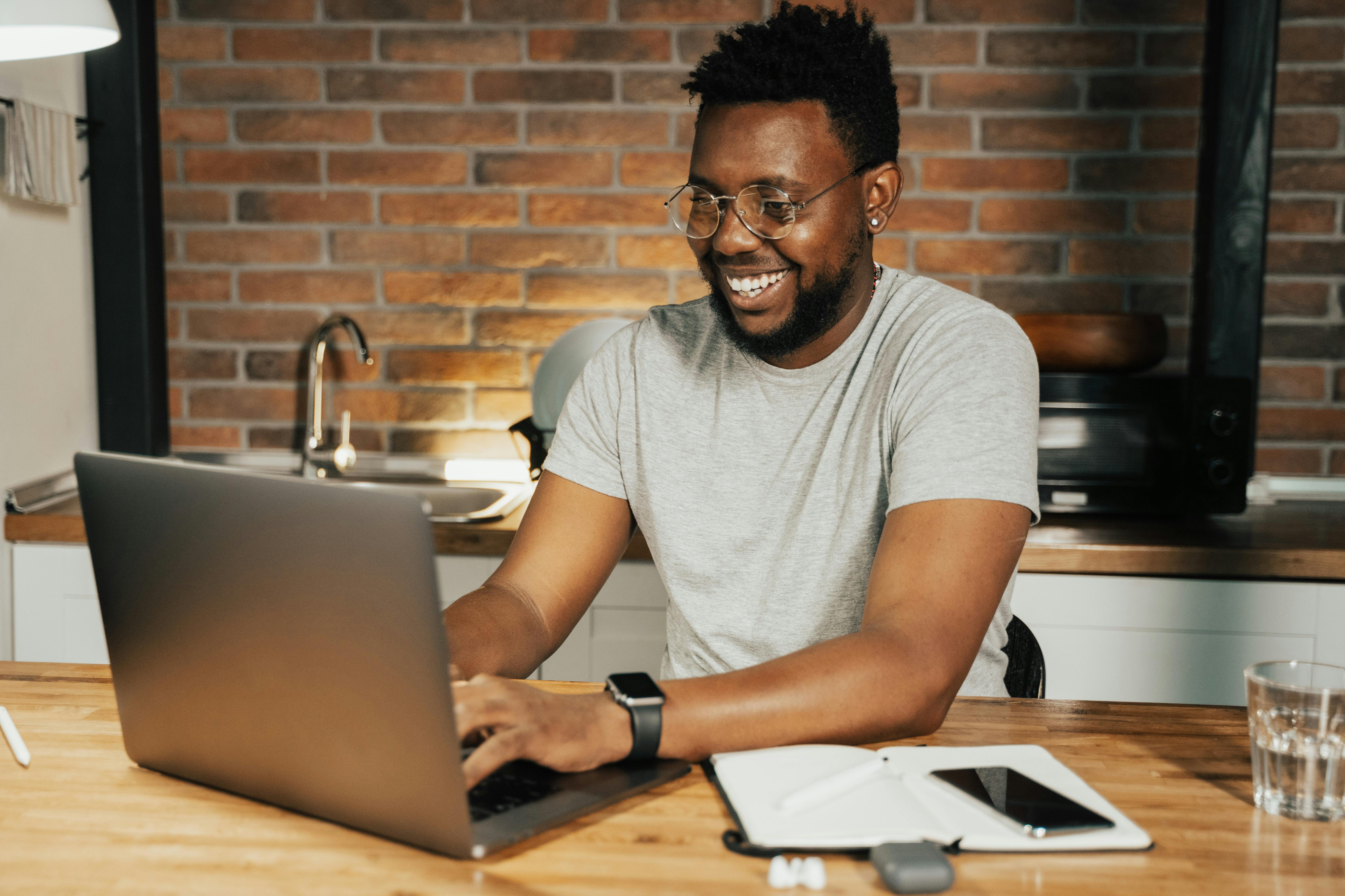 A man typing on his laptop looking happy.