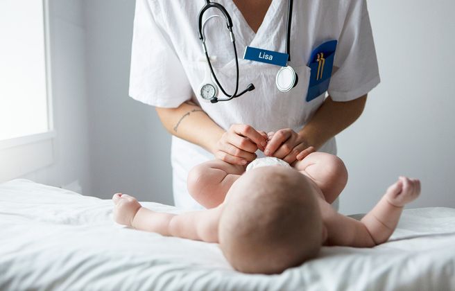 Läkare undersöker bebis på sjukhussäng