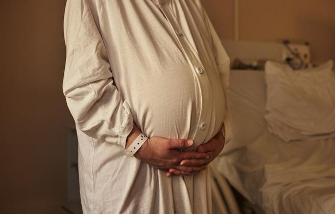 Gravid kvinna håller sig på magen