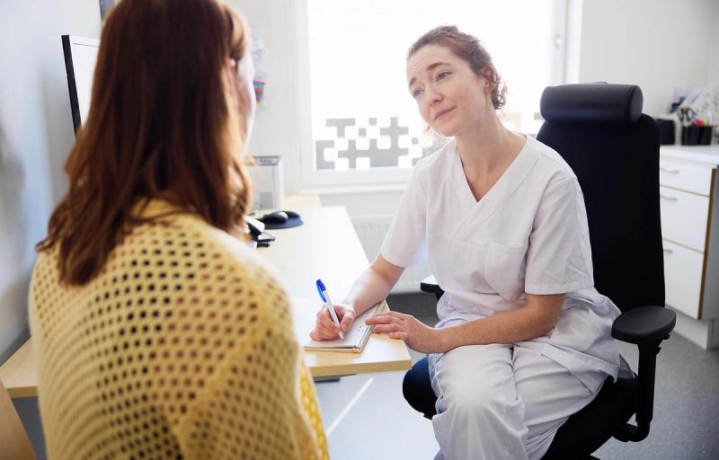Läkare pratar med kvinnlig patient.