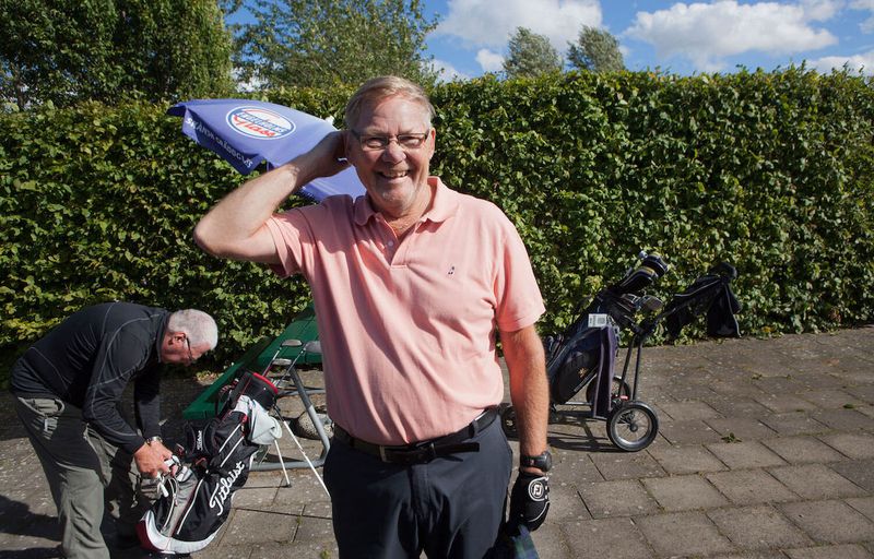 Man i golfkläder med golfbag i bakgrunden