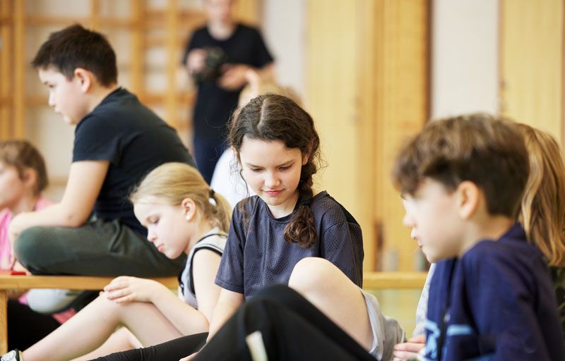 Barn i gympasal som lyssnar på instruktioner.
