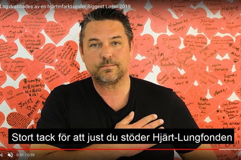 Man framför vägg av hjärtan håller sig mot hjärtat