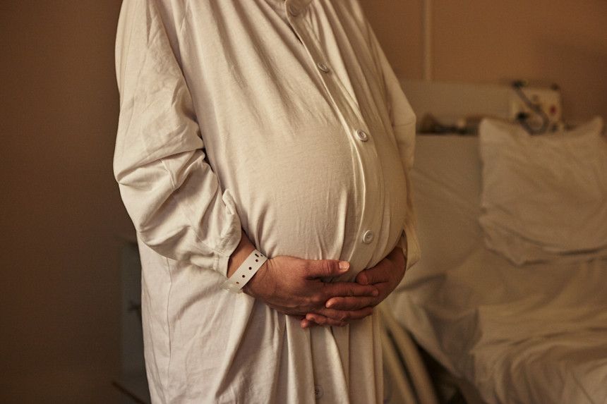 Gravid kvinna håller händer runt magen