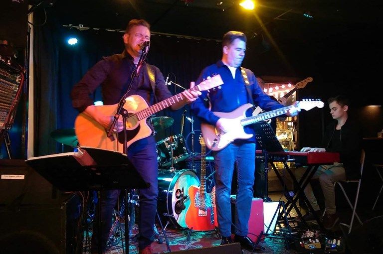 Två män med gitarrer på en scen