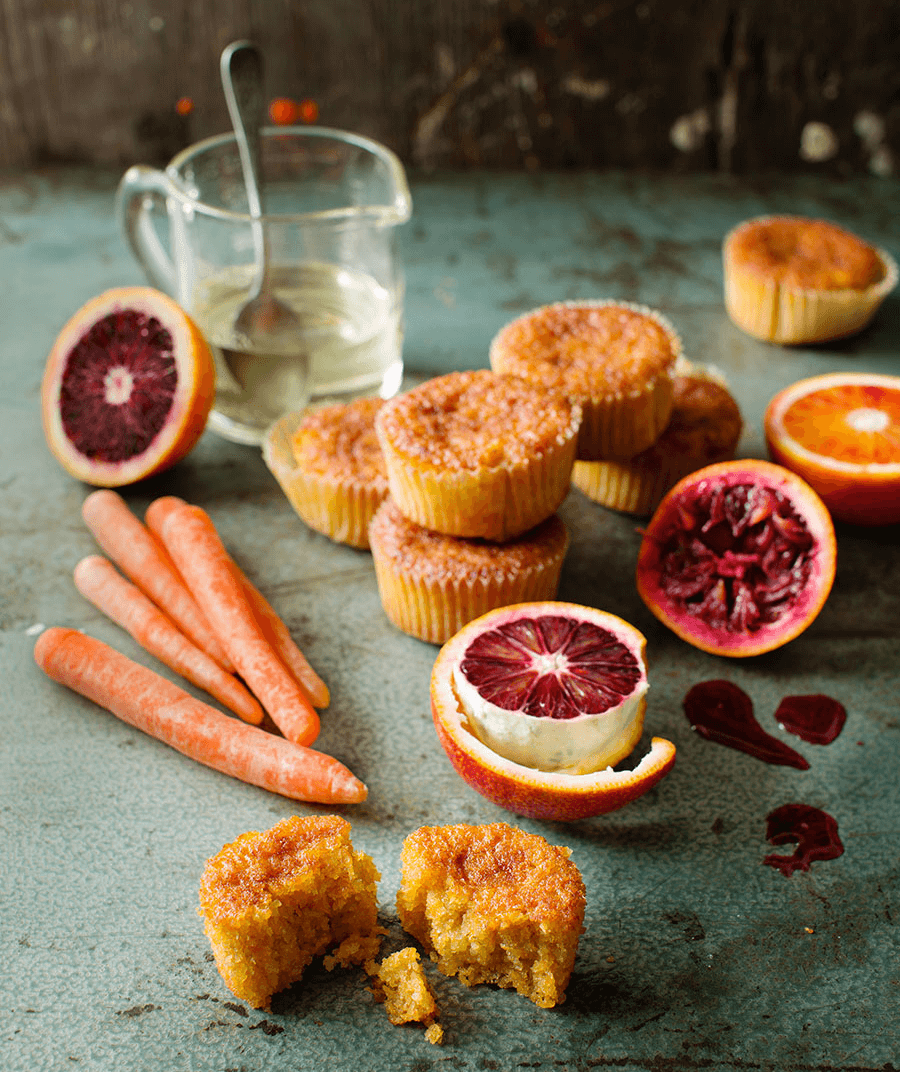 Muffins med bland annat morot, i ett stilleben på ett bord med grönsaker.