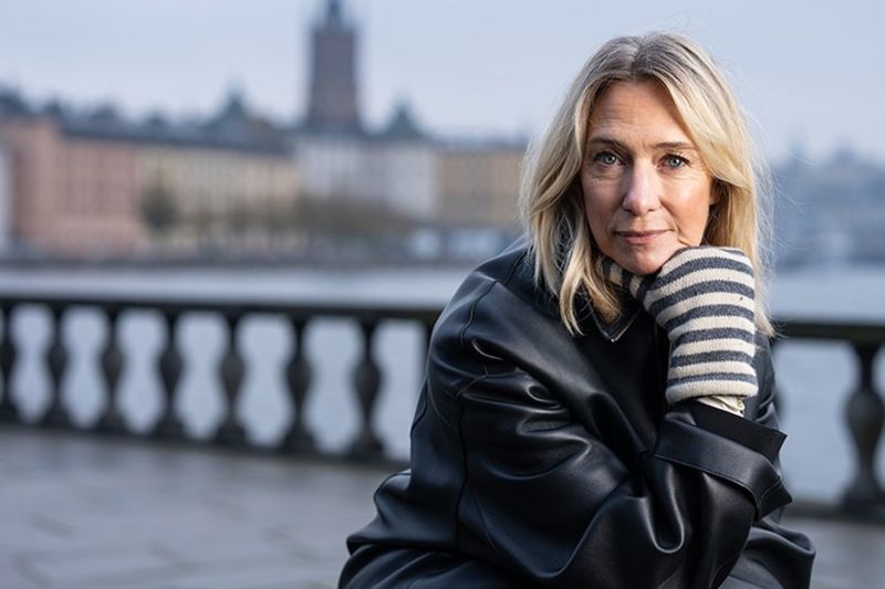 Victoria Dyning sitter utanför Stadshuset i Stockholm med vattnet bakom sig.