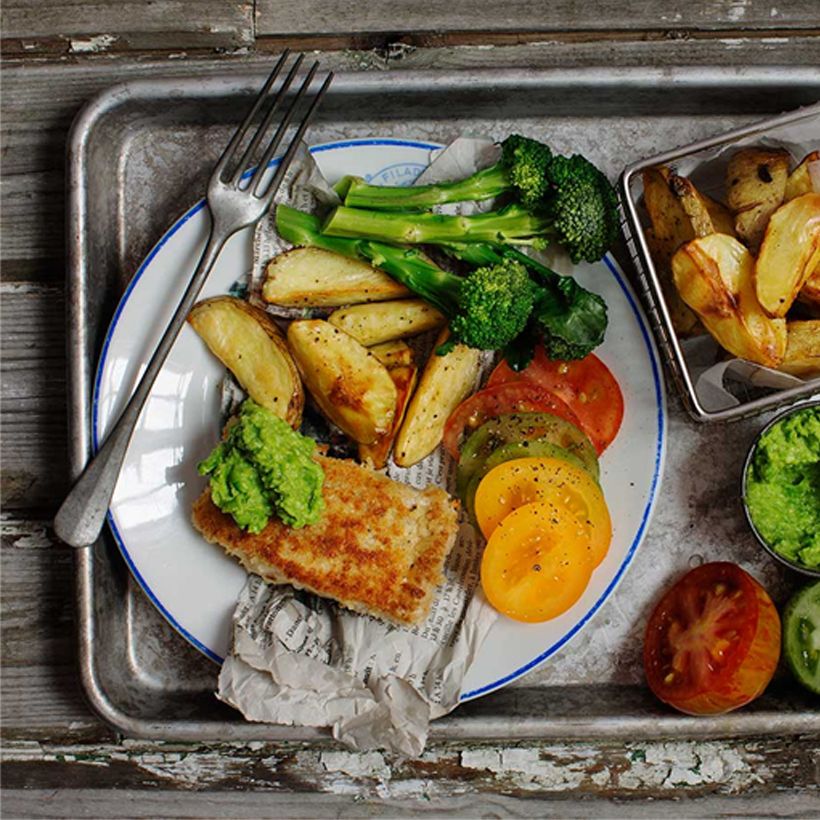 Fish n' chips med tillbehör serverat på en tallrik.