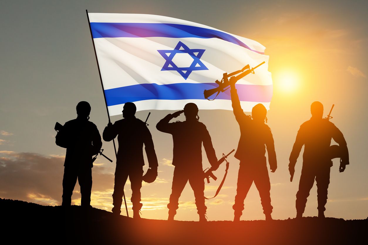 Silhouettes of soldiers with Israel flag against the sunrise in the desert. Israel armed forces.