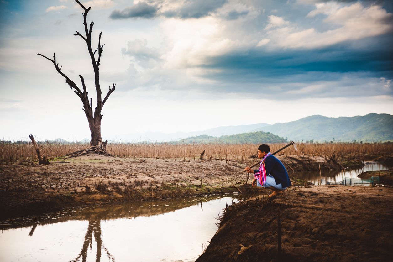 A Myanmar farmer sits on cracked, parched earth beside a drying water body. The UN says El Niño is expected to leave 49 million more people food insecure by the end of 2027. Photo: iStock