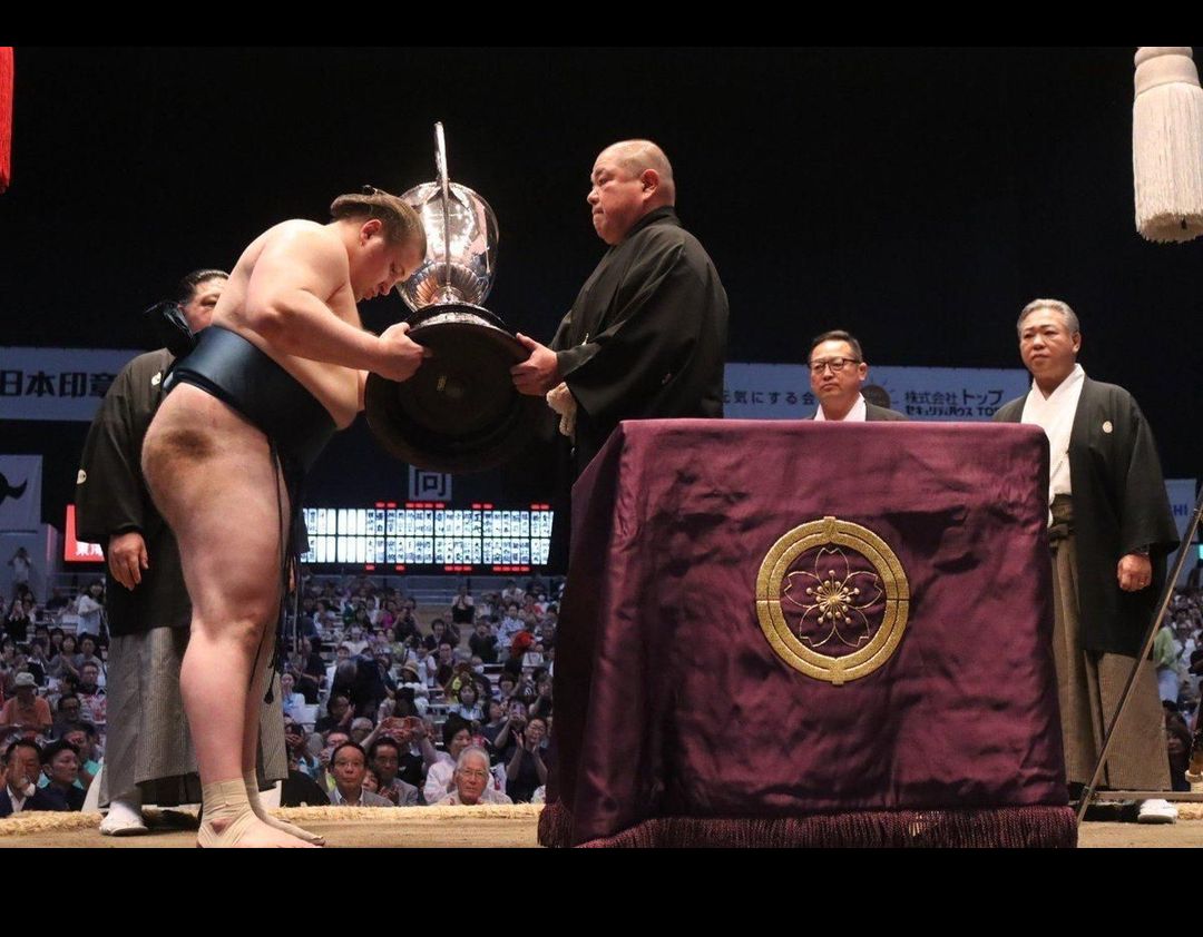 Aonishiki receives the Emperor’s Cup from JSA chairman Hakkaku after winning the New Year Grand Sumo Tournament at Ryogoku Kokugikan in Tokyo on January 25, 2026. Photo: X / Japan Sumo Association.