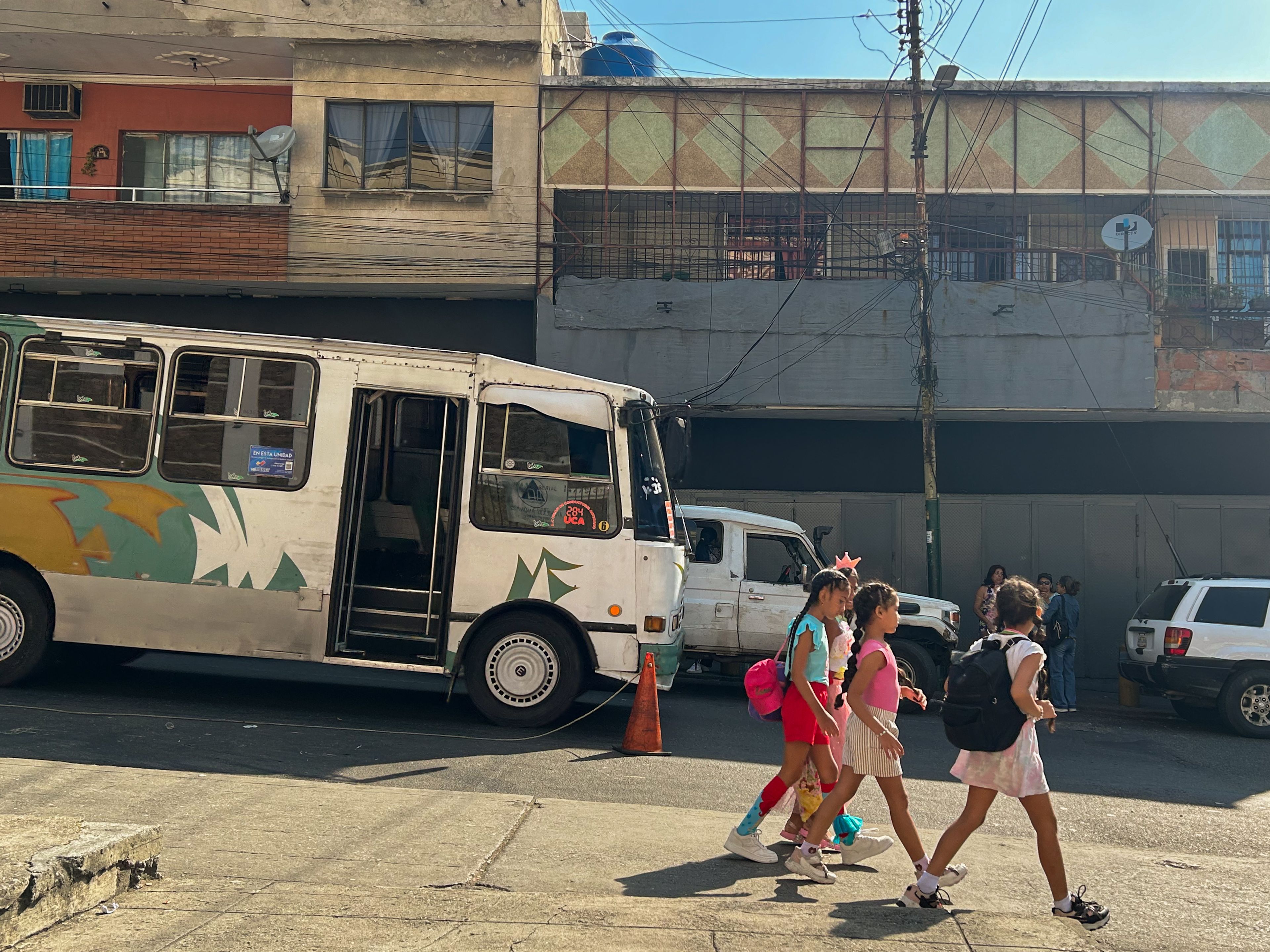 Children walk past a bus on a street in Caracas. Photo: María José Dugarte