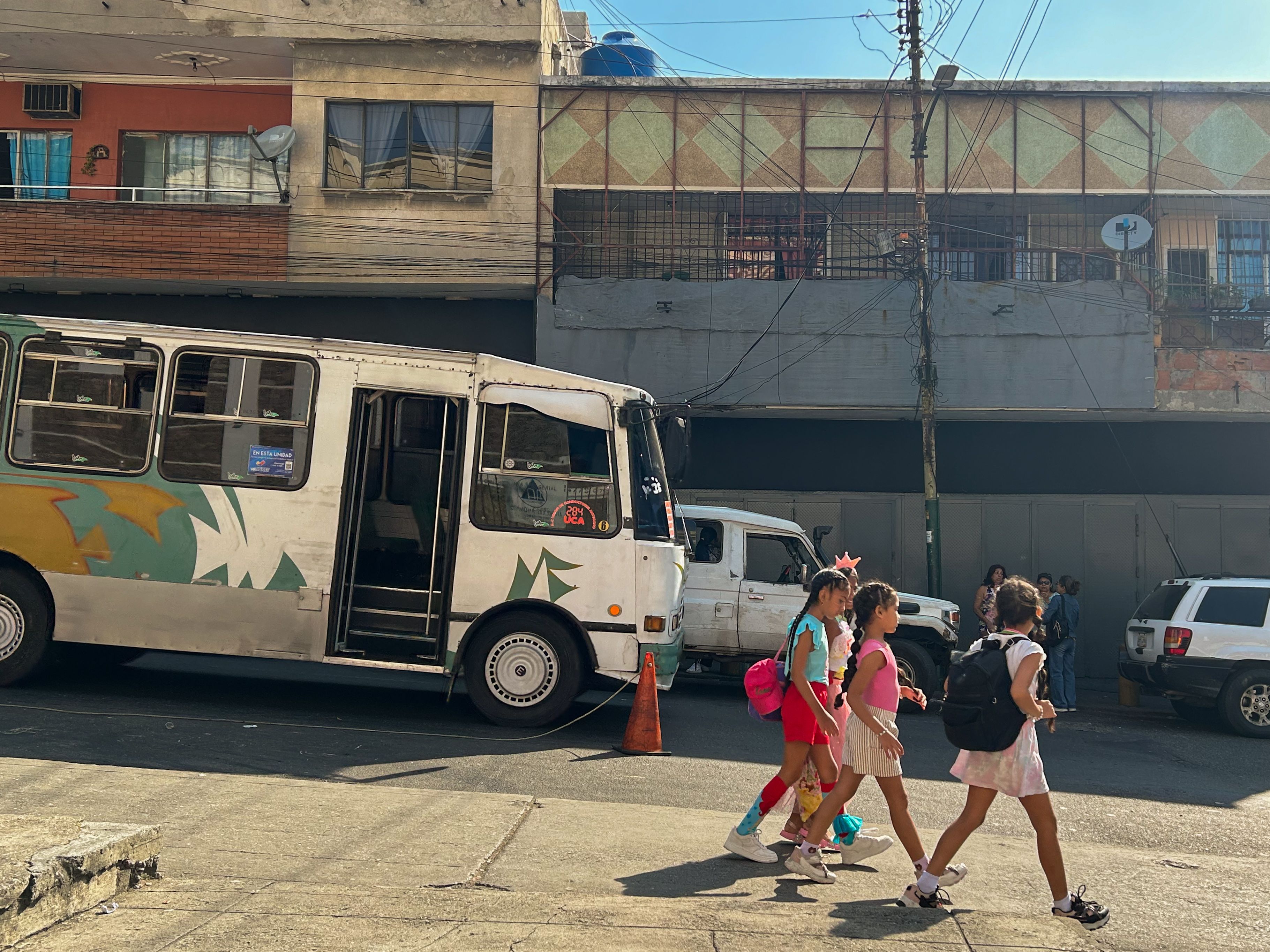 Children walk past a bus on a street in Caracas. Photo: María José Dugarte