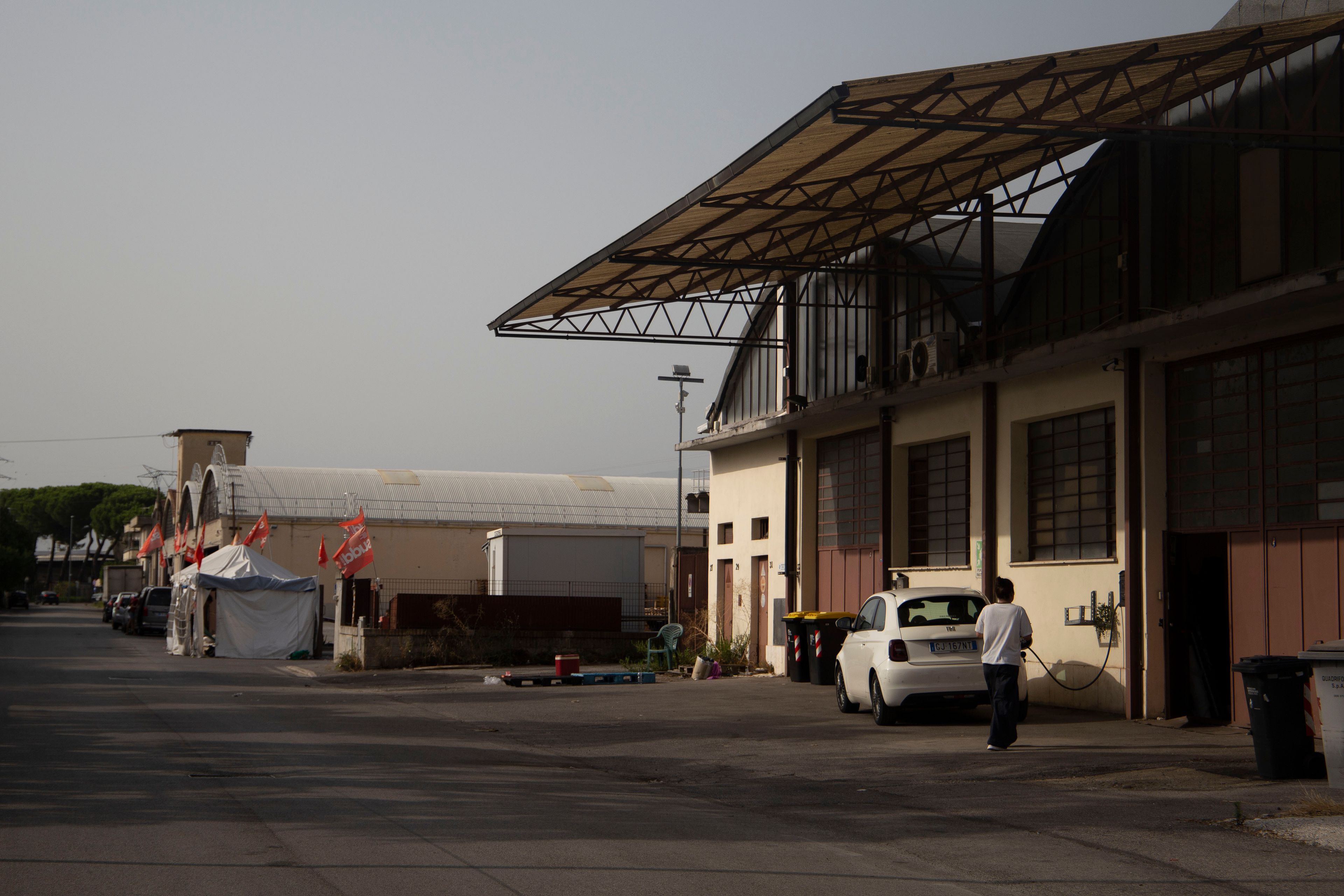 Acca’s premises in Campi Bisenzio, Italy, with picket lines and one of the tents where trade unionists and workers slept during the months-long protest. August 2026. Photo: Monica Pelliccia