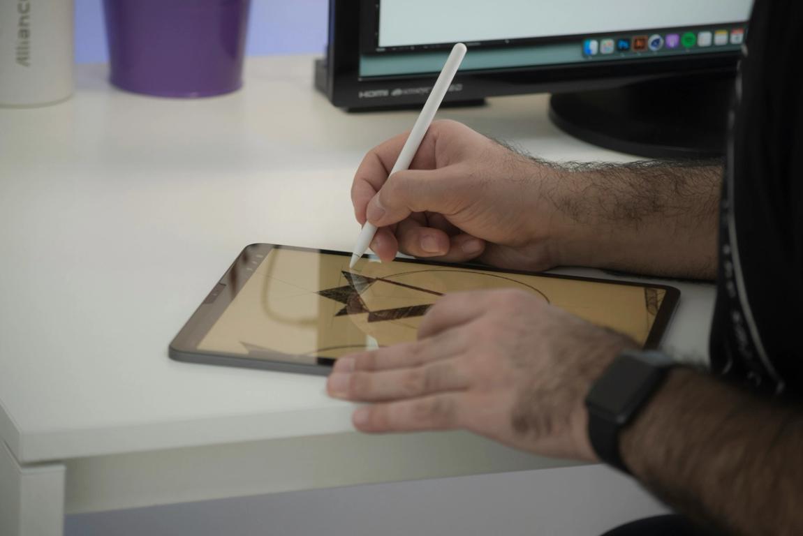 a man is drawing on a tablet with a pencil .