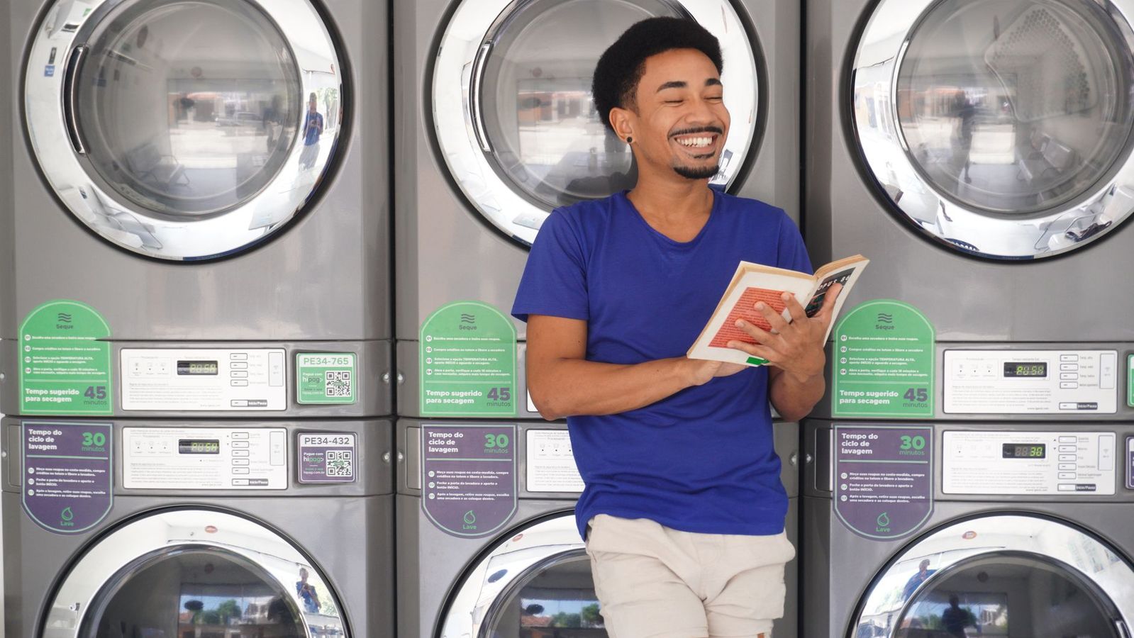 Student reading in a laundromat while washing clothes near campus housing