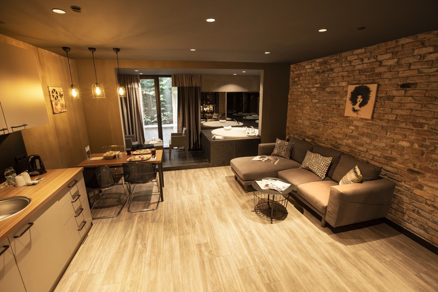 CITYLOFT 161 Jacuzzi Suite: Küche, Esstisch und Sofa vor einer Backsteinwand