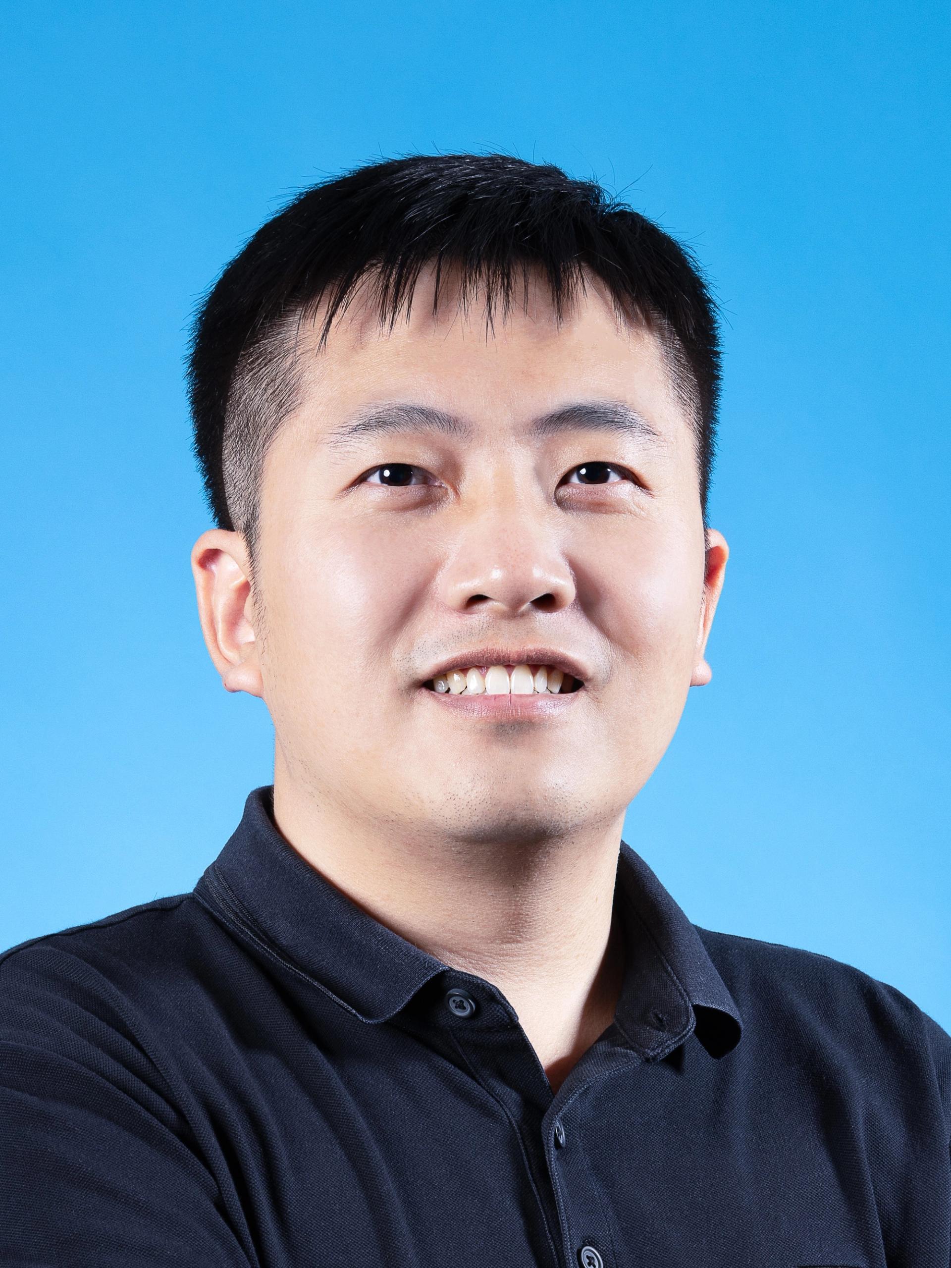 Fangyang Hu against a blue background wearing dark collared, button-up shirt.