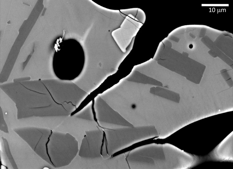 Microtextures in a basaltic volcanic ash grain, showing broken crystal in an intact matrix and white suture lines where magma healed.