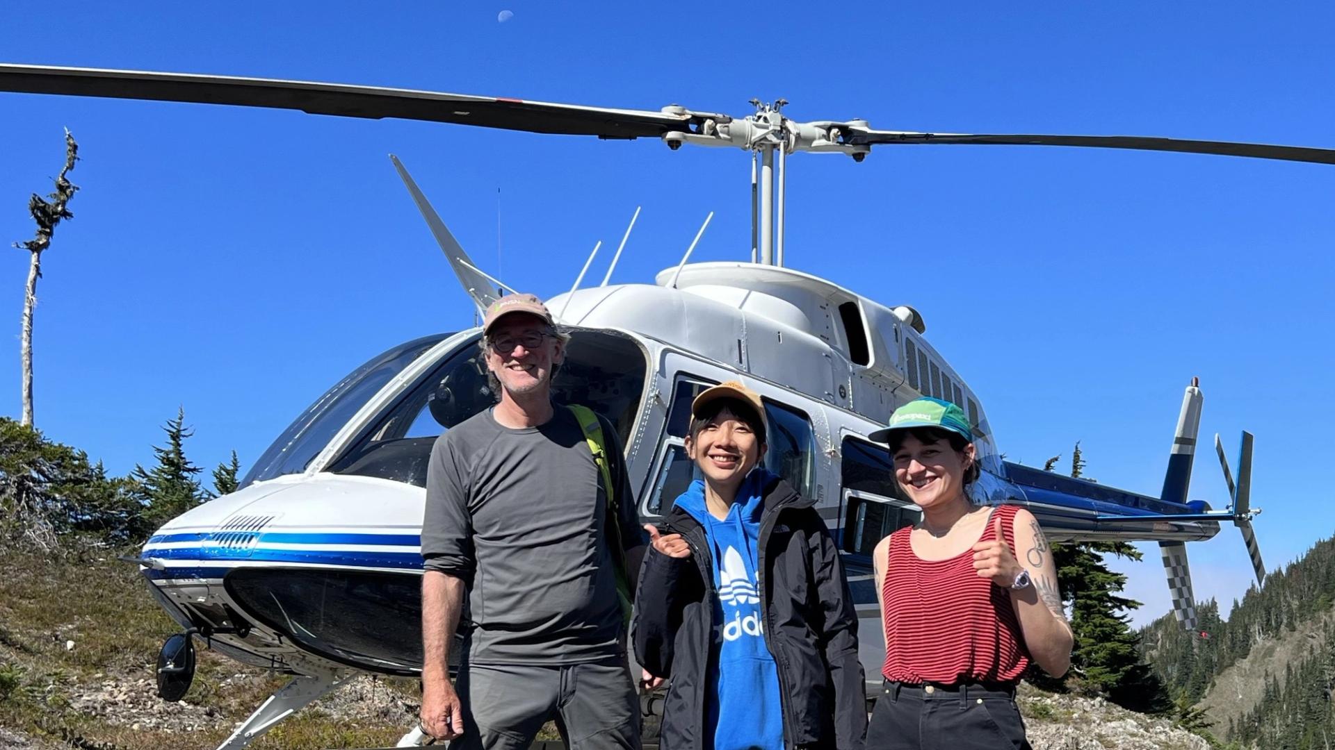 Students & professor in the field in front of helicopter