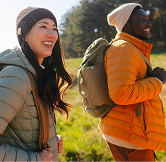 Two students smile with backpacks on a hike.