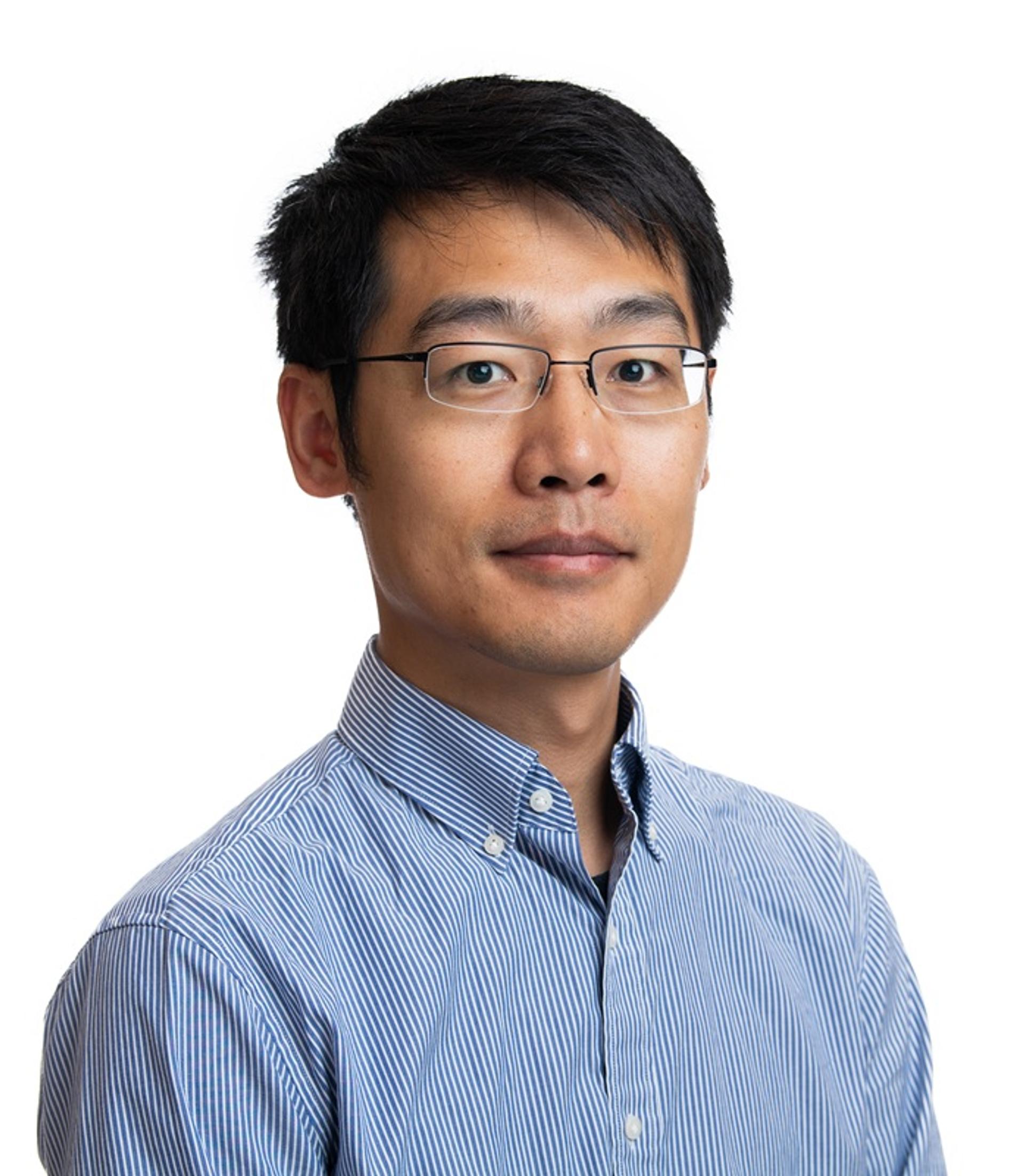 Wentao Cao against a white background with a blue and white striped button down, collared shirt and glasses.