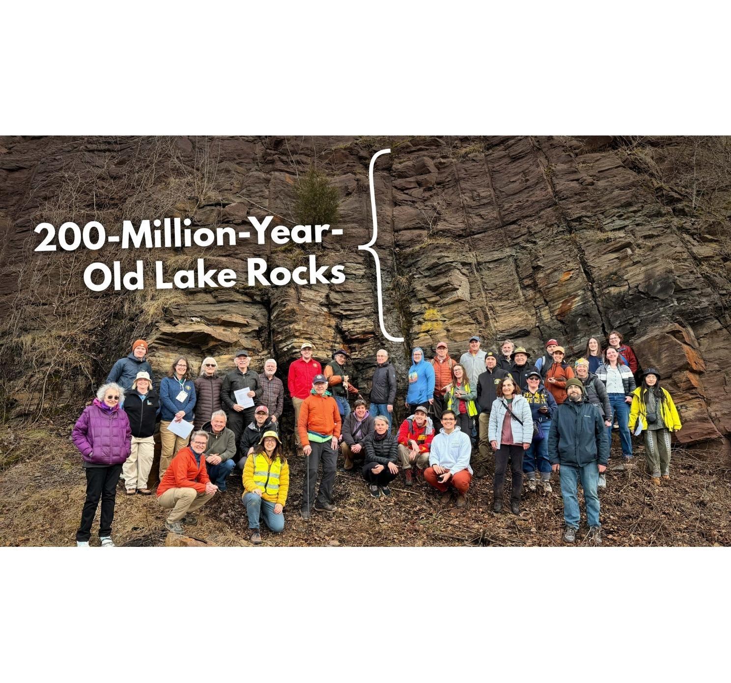 YouTube thumbnail image of GSA Field Trip participants posing in front of large outcrop of Jurassic rocks in Connecticut