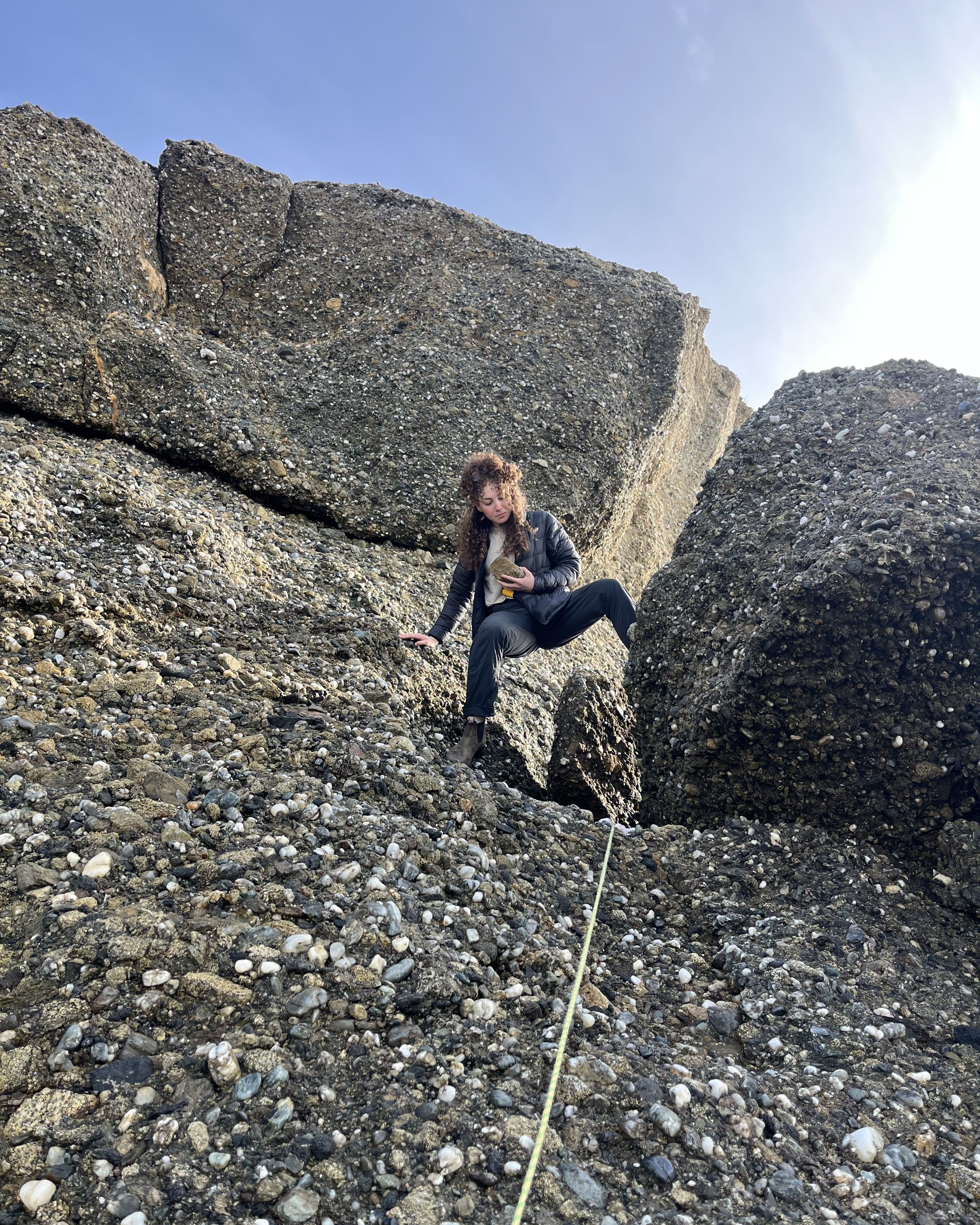 Photo of GSA graduate student research grant recipient conducting geoscience research in the field looking at rock while climbing a mountain