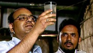 A man holds up a glass of water.