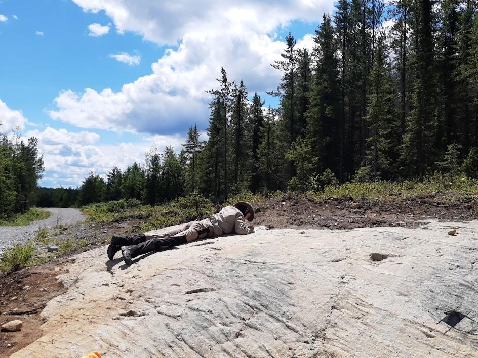 Photo of GSA Graduate Student Research Grant Recipients conducting fieldwork laying down examining a rock close up
