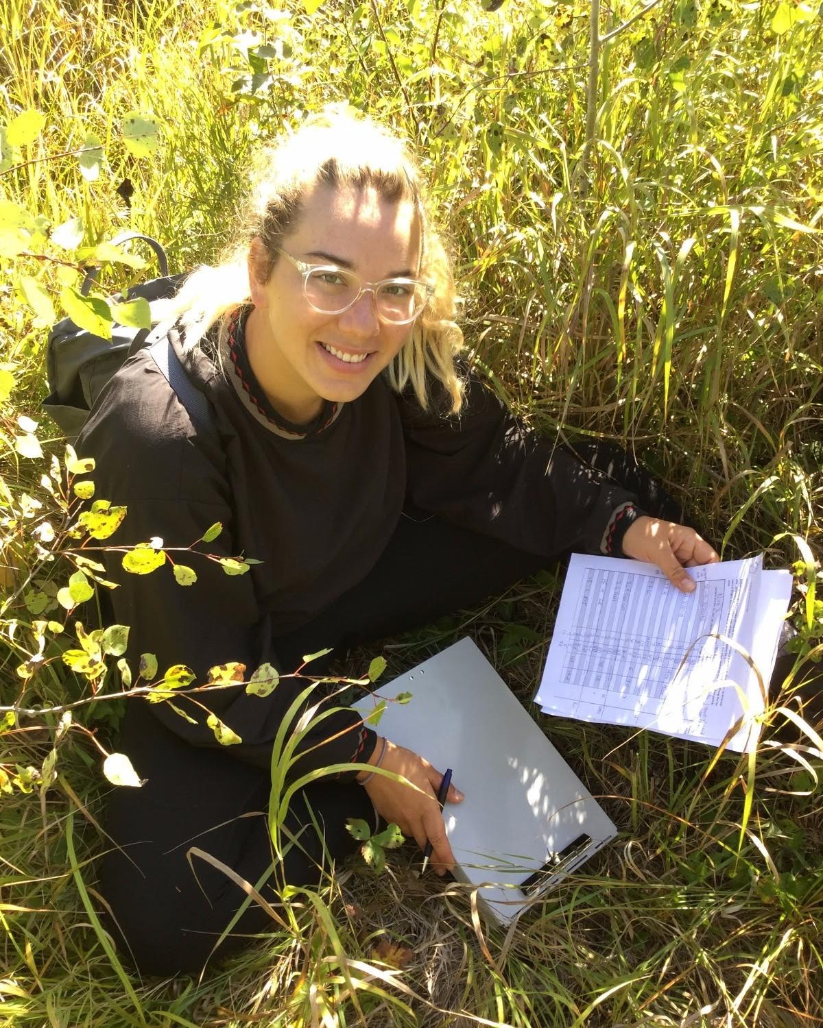 Photo of GeoCorps Participant in the field holding notes